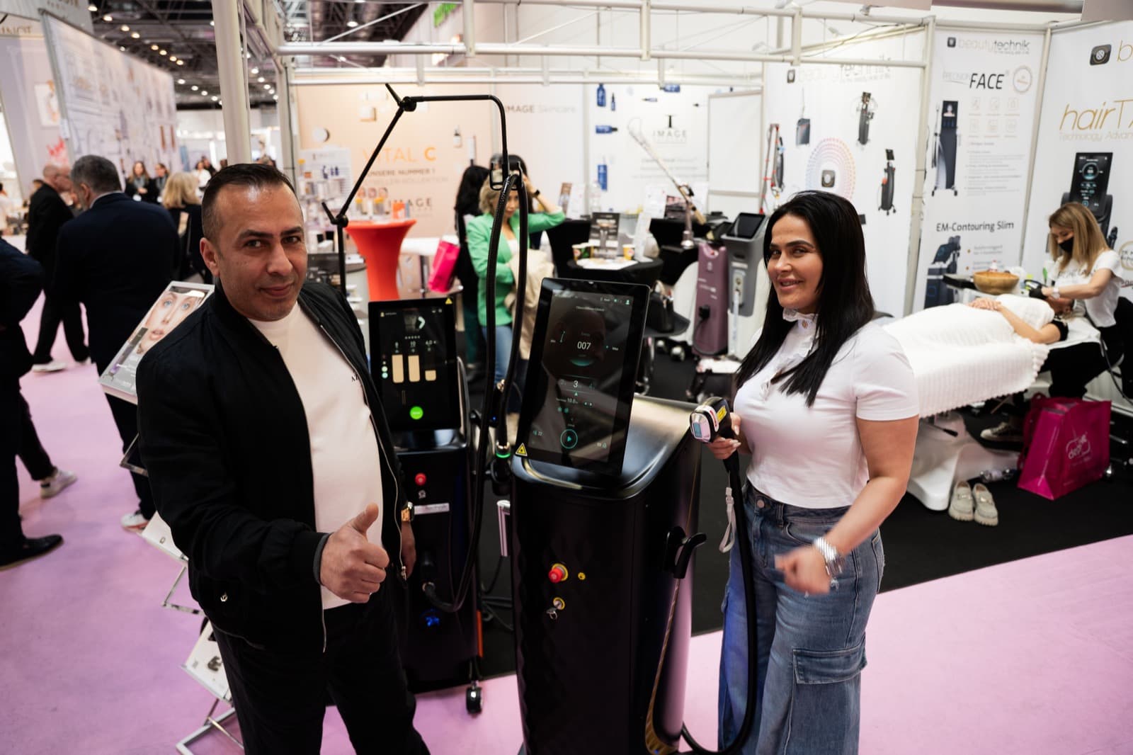 Zwei Personen an einem Messestand mit Beauty-Geräten.